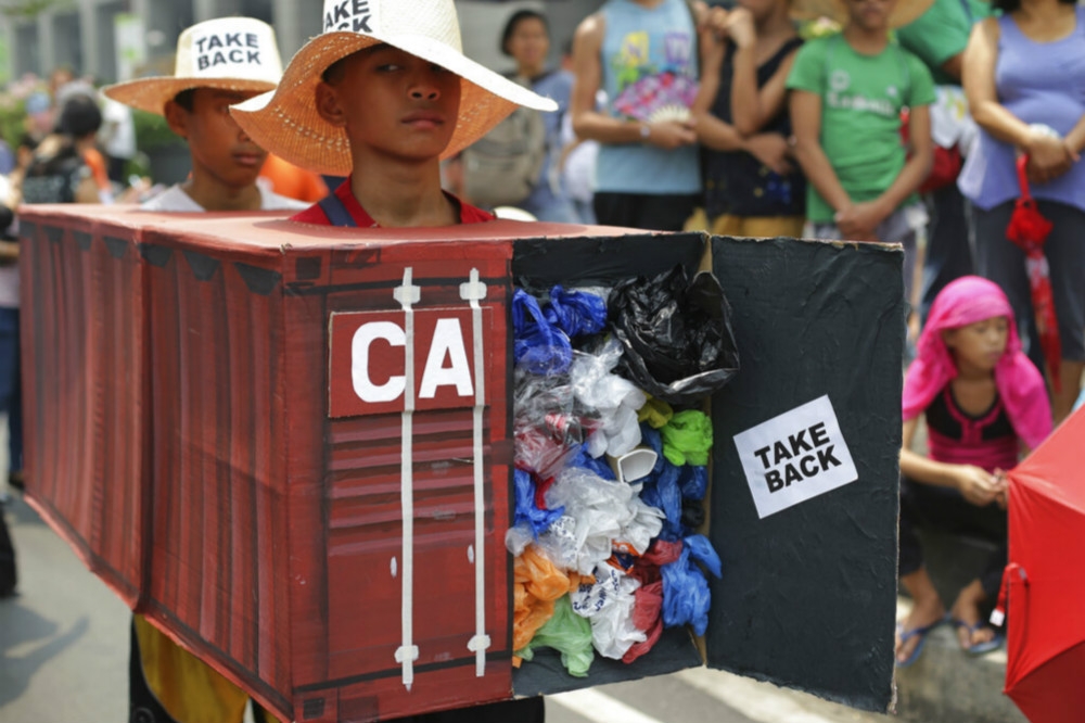 菲律賓民眾以道具和行動劇，要求加拿大把裝有廢棄物的貨櫃運回去。（美聯社）