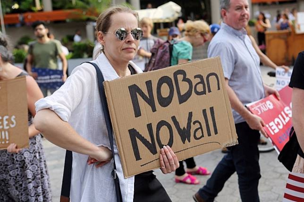民眾在紐約街頭高舉抗議旅行禁令的牌子。（湯森路透）