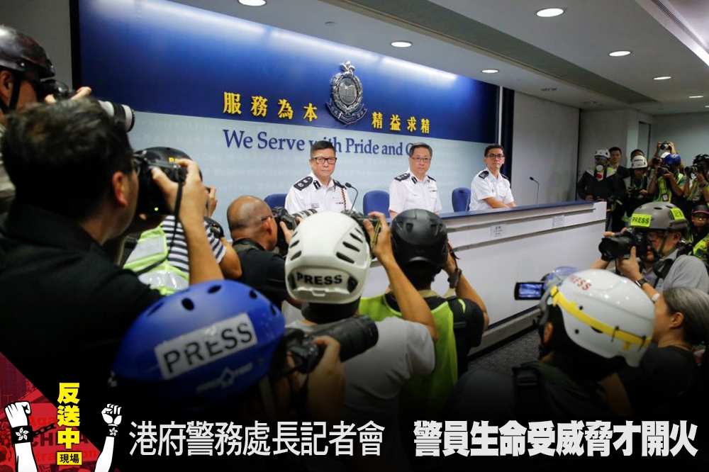 香港警務處長盧偉聰（右二）13日晚間召開記者會，採訪記者刻意穿戴防毒面具與背心，抗議港警12日的暴力行為。（照片：湯森路透，後製：潘世惟）