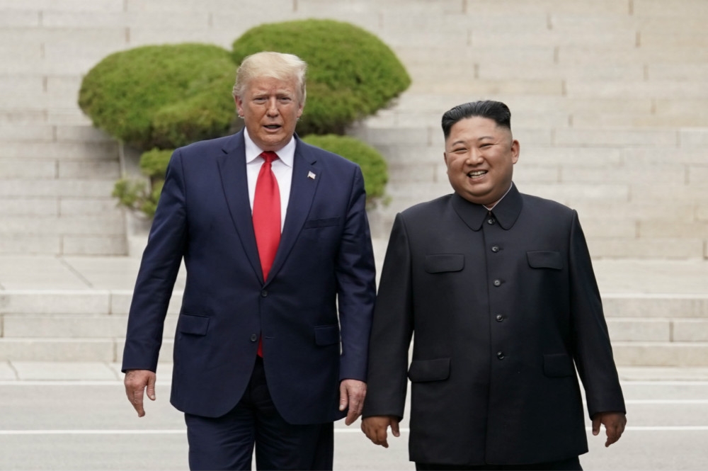 美國總統川普（左）與金正恩（右）越過38度國界後，從北韓國土走回南韓側。（湯森路透）