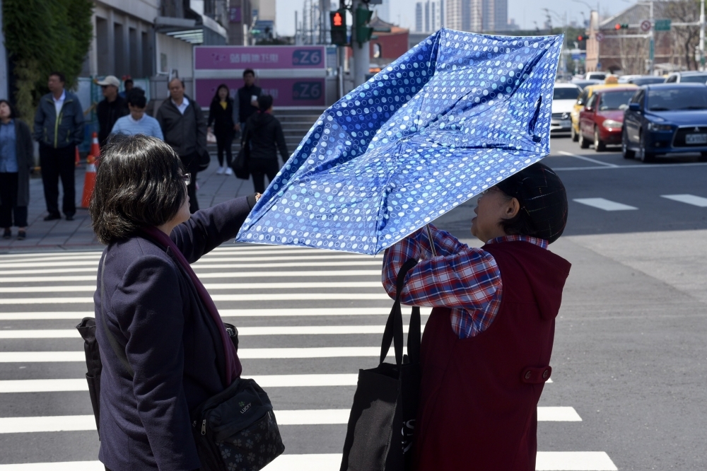 在大太陽下曬一會兒就暈了，行人們紛紛拿出陽傘遮蔭。（資料照片／張文玠攝）