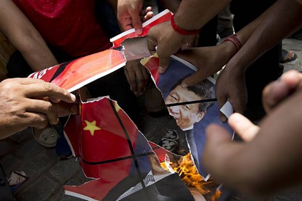 印度人民撕裂習近平與中國國旗照片。（湯森路透）
