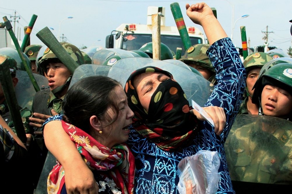 2名中國新疆烏魯木齊的維吾爾族婦女遭中國解放軍包圍。（湯森路透）