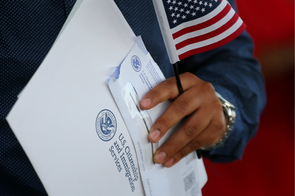 移民手持美國移民局文件準備進行宣誓。（湯森路透）