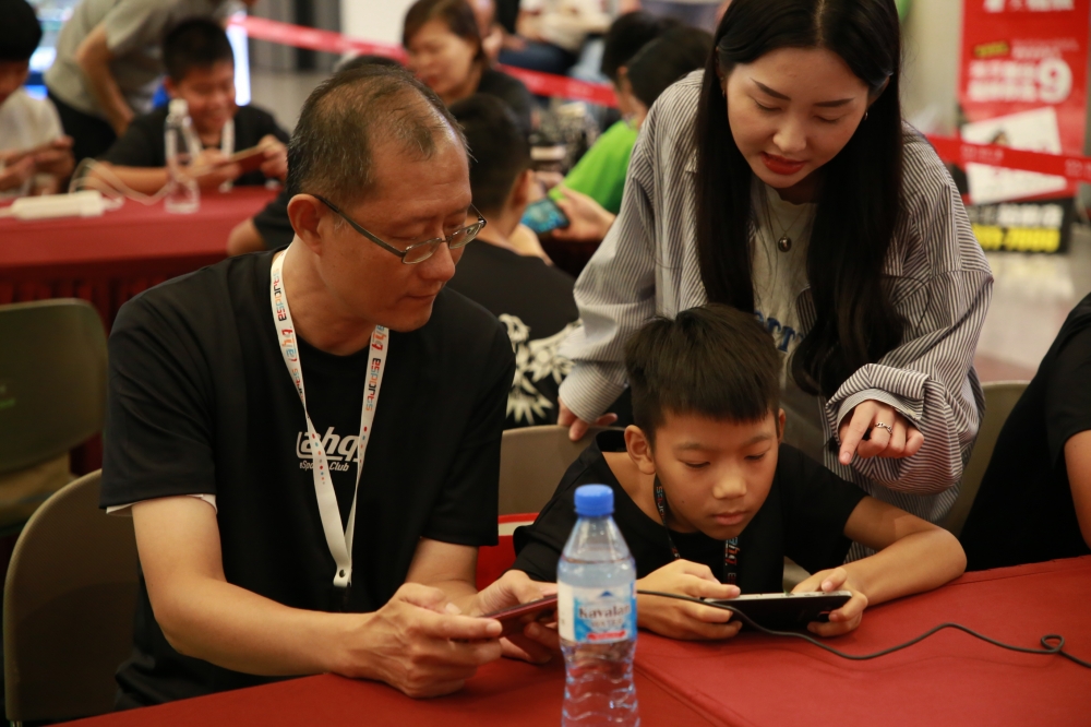 ahq職業電競俱樂部與新光人壽合作舉辦首屆電競營，著重親子溝通與電競體驗，圖為助教正在指導親子一同進行《傳說對決》手機遊戲。