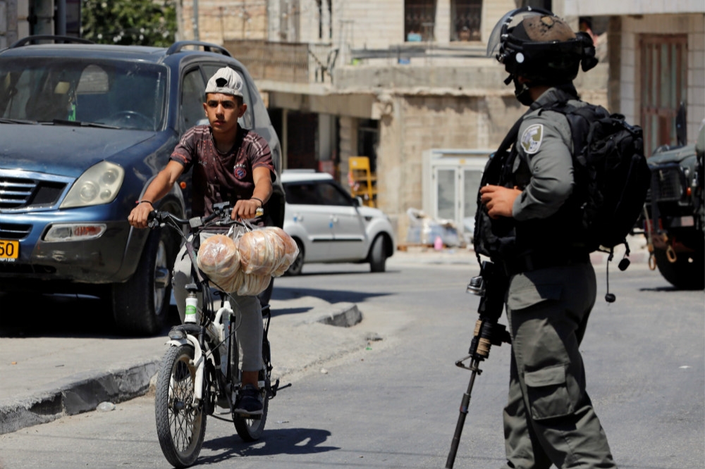 以色列國防軍官兵（右）與巴勒斯坦少年（左）。（湯森路透）