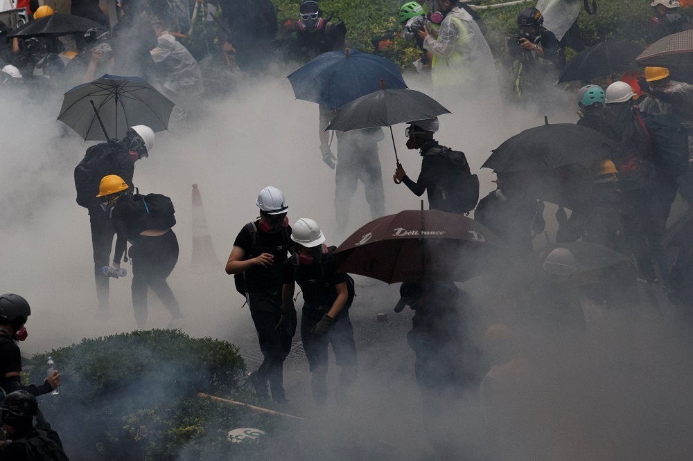 香港荃灣示威者25日遭警方發射的催淚瓦斯包圍。（湯森路透）