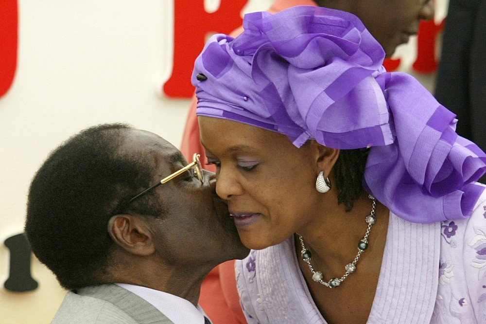 2004年2月21日，非洲國家辛巴威前總統穆加比，在80歲生日派對親吻妻子格蕾絲。（湯森路透）