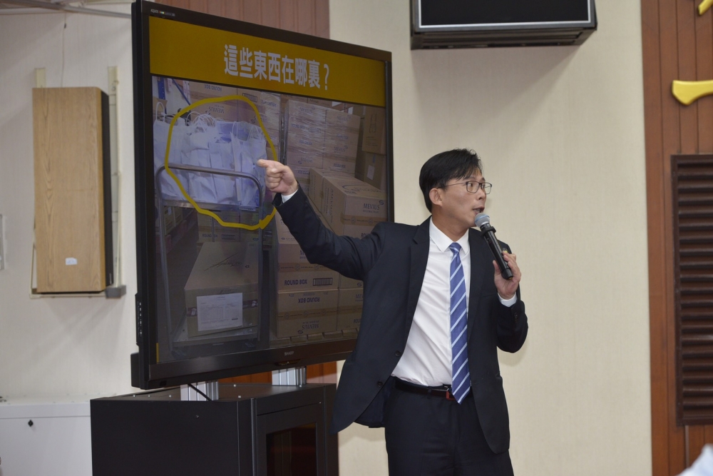 立院私菸案報告上，黃國昌揭示一張照片，畫面的大批菸品上有許多白色塑膠袋，之後下落不明，他質問是誰帶走的。（李智為攝）