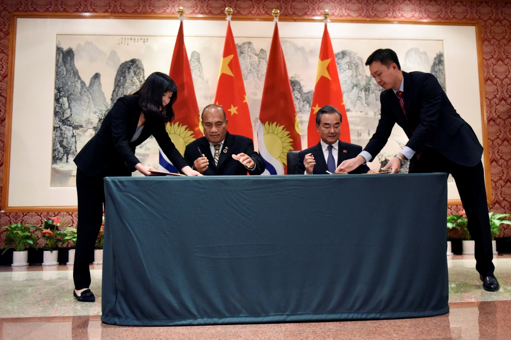 中國國務委員兼外交部長王毅（右）與吉里巴斯總統兼外交部長馬茂（左）在紐約簽署聯合公報，正式復交。（湯森路透）