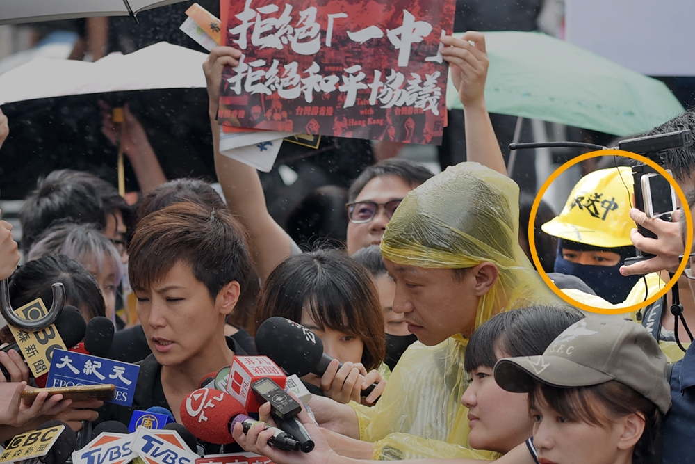 香港反送中運動的香港歌手何韻詩29日參加台港大遊行，居然遭一名戴著頭套、安全帽只露出眼睛的男子（紅圈處）潑灑紅色油漆。（蔣銀珊攝）