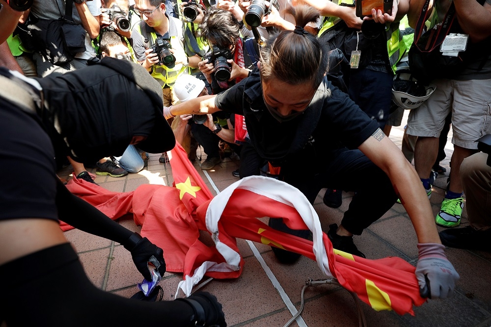 一名香港抗議者撕毀中國國旗。（湯森路透）