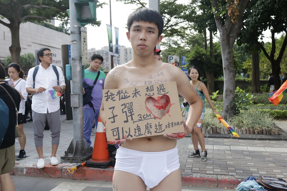 香港反送中抗爭者「微」來台參與，他胸口塗上紅色顏料，手持寫著「我從未想過子彈可以這麼近」紙板，默默抗議香港警察執法過當。(王良博攝)