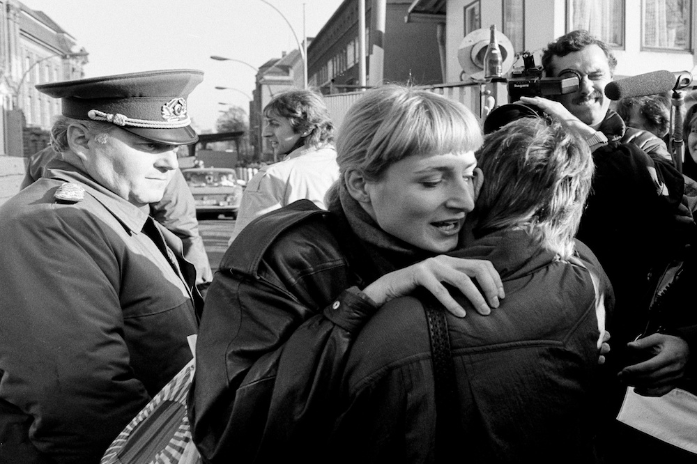 1989年柏林圍牆倒塌後，分別來自東西德的兩位婦女，站在檢查哨前相擁。（湯森路透）