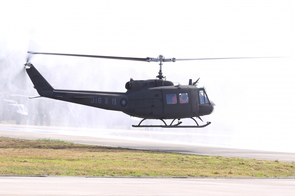 UH-1H直升機30日舉行除役典禮，由兩輛消防車噴灑水幕形成拱門，UH-1H直升機則滯空緩緩滑行通過水門洗禮。（王傳豪／攝）