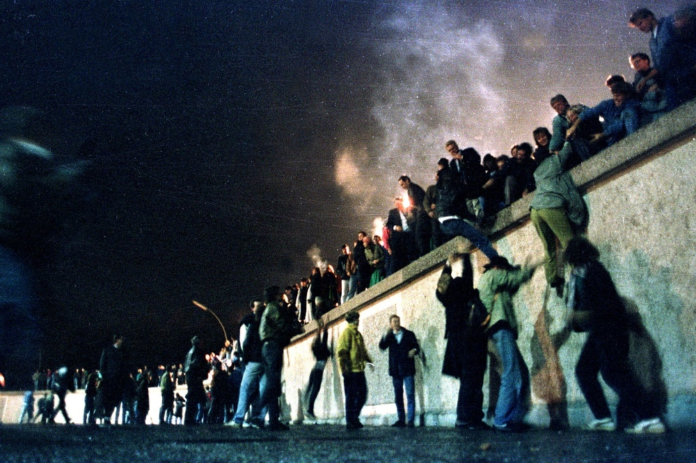 1989年11月，民眾攀上柏林圍牆（Berlin Wall）。（湯森路透）