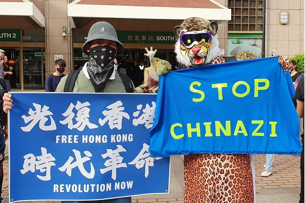 作者持「STOP CHINAZI(反赤納粹)」標語參加台北車站撐香港反送中 「面具無罪」 快閃行動。（作者提供）