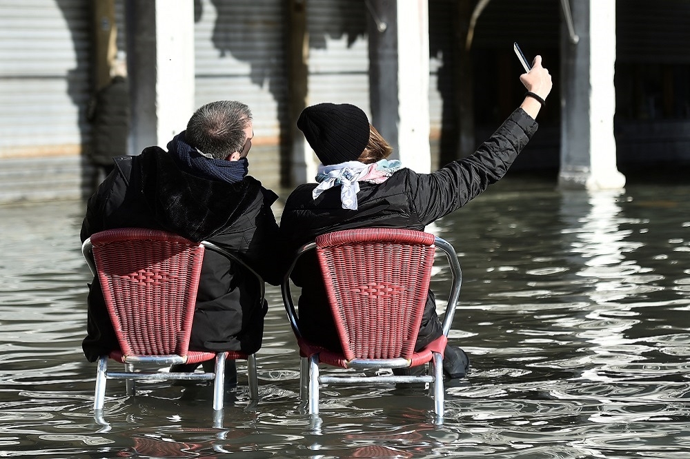 義大利威尼斯（Venice）超過85%地區12日深陷水患之苦，當地民眾苦中作樂搬椅子自拍。（湯森路透）