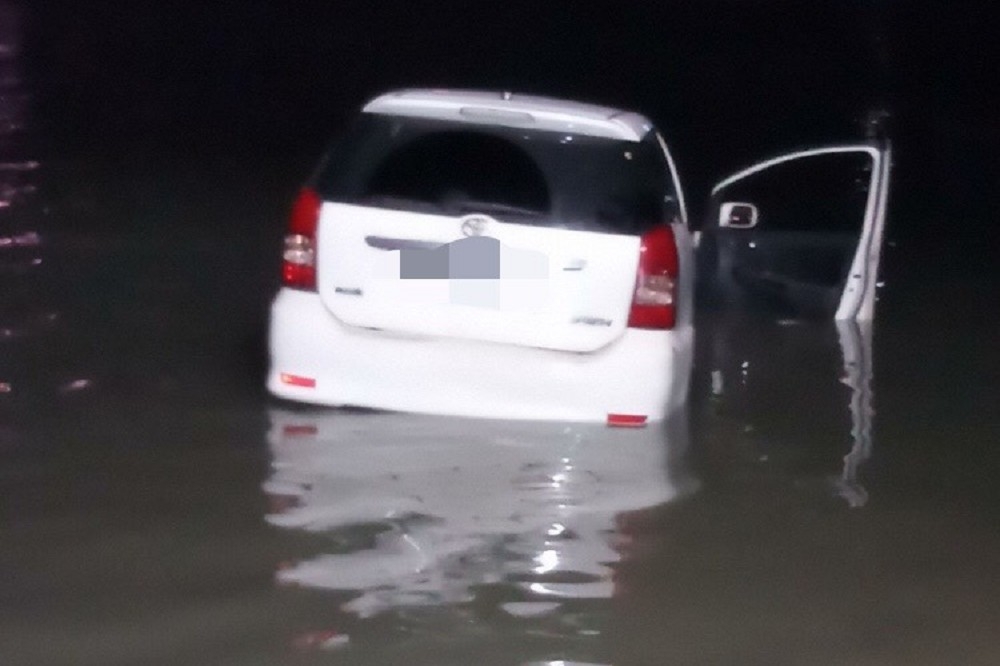 八里區渡船頭街碼頭下，有一輛白色汽車衝入河中，所幸車中2人於晚上7點36分脫困。（ 新北消防局提供）