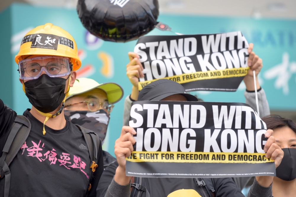 有反送中的香港人14日在花博爭豔館的馬拉松博覽會現唱，穿戴黑衣、口罩唱「願光榮歸香港」。（張哲偉攝）