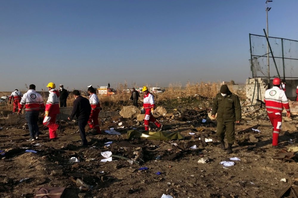 伊朗當地救難人員正進行墜機現場清理作業。（湯森路透）