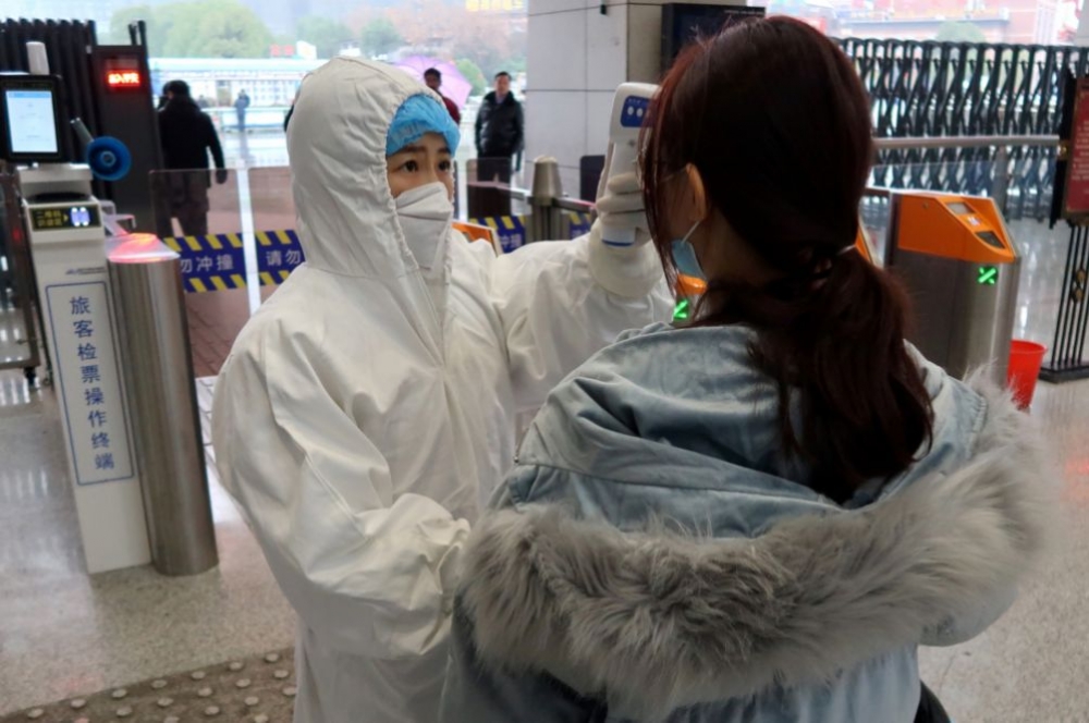 中國湖北省咸寧市醫護人員為乘客量額溫。（湯森路透）