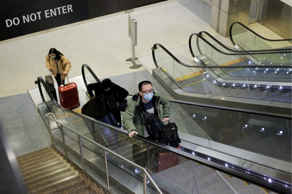 來自中國的旅客戴著口罩抵達美國西雅圖機場。（湯森路透）