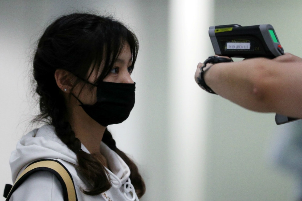 旅客在香港機場接受額溫測量檢疫作業。（湯森路透）
