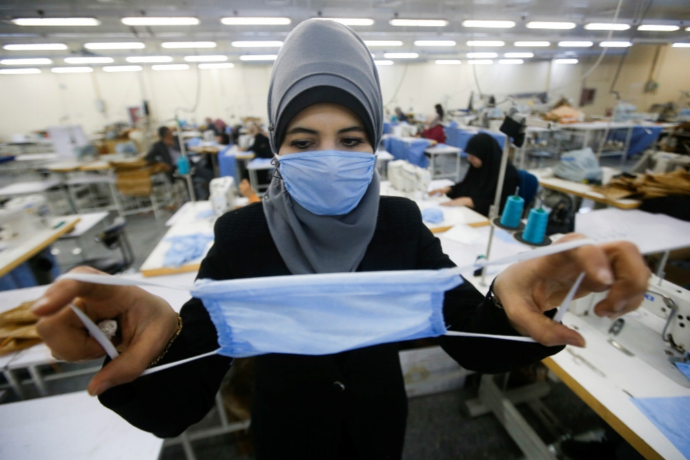 伊拉克女工正在檢視口罩的品質。（湯森路透）
