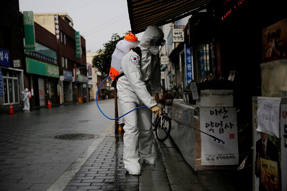 南韓軍方人員在大邱街道協助消毒。（湯森路透）