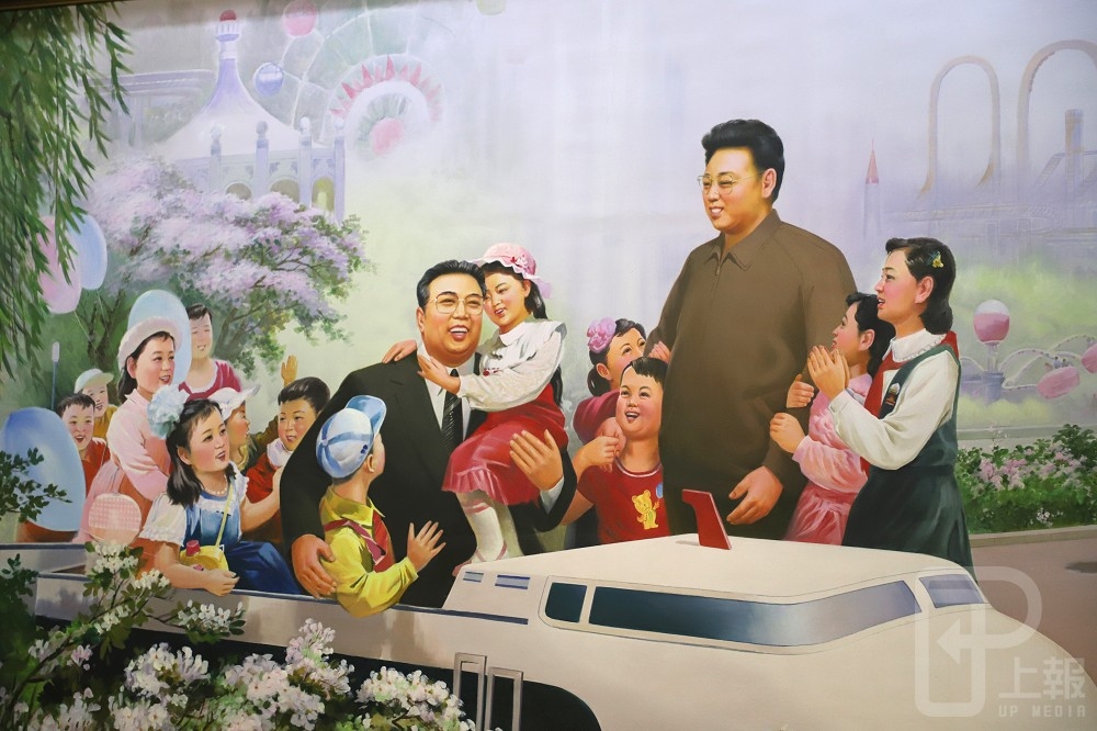 北韓當局指定外賓觀摩教育處所之一的康盤石中學，穿堂牆上掛著已故領導人金日成和金正日，與象徵國家棟樑的孩子們快樂相處的畫像。（攝影：羅佳蓉）