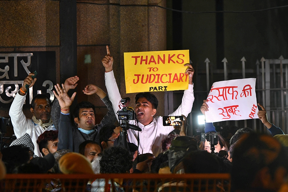 印度民眾20日在監獄外慶祝4嫌執行絞刑，舉起「公義得彰」的標語。（湯森路透）
