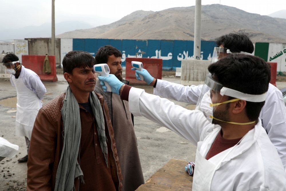 阿富汗防疫人員測量體溫。（湯森路透）