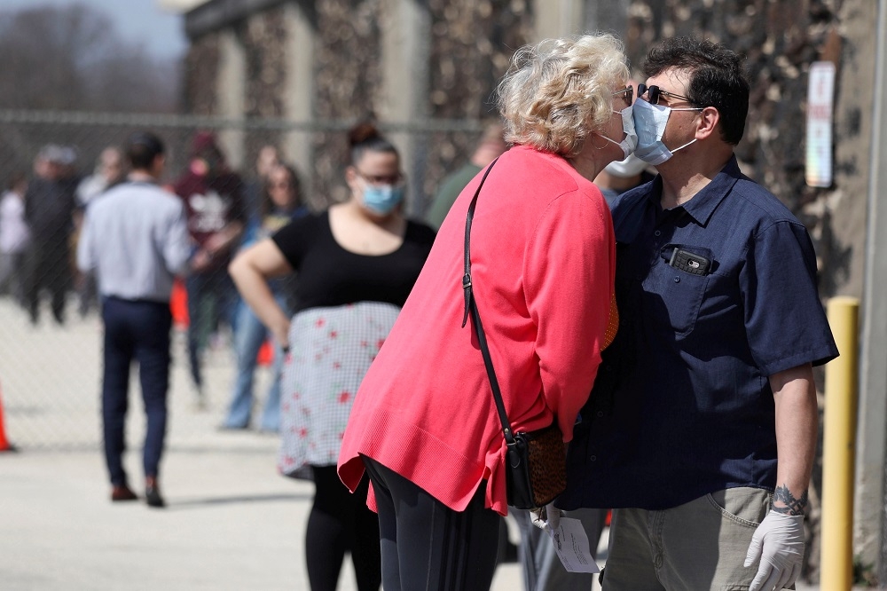 全美疫情嚴峻，威斯康辛州民眾隔著口罩當街相吻。（湯森路透）