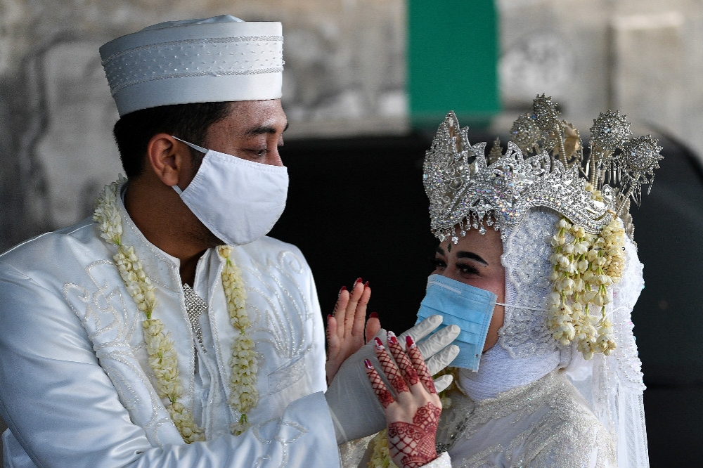 印尼穿著傳統服飾的新婚夫妻，戴上口罩舉行婚禮。（湯森路透）