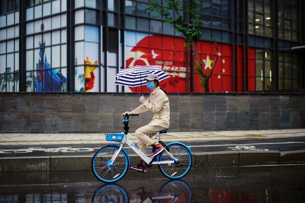 一名女子騎著共享腳踏車在武漢街頭。（湯森路透）