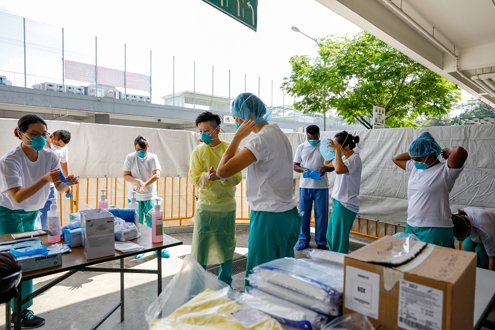 新加坡醫護人員在進入S11榜鵝外勞宿舍前進行防護準備。（湯森路透）