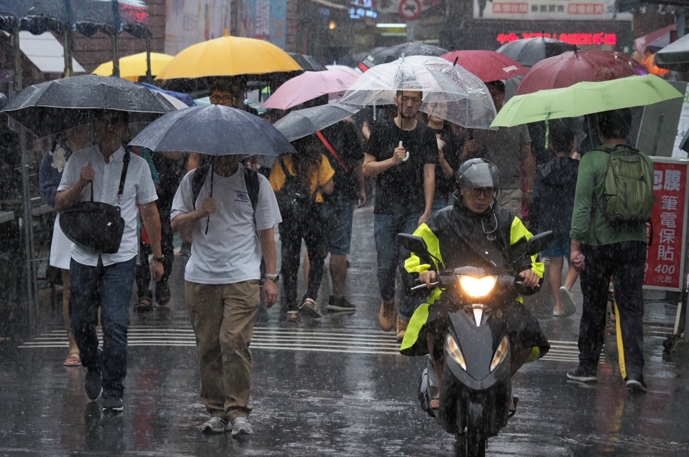 受颱風外圍環流及午後對流發展旺盛影響，氣象局持續發布豪雨特報，民眾外出要記得帶傘。（資料照片／張家銘攝）