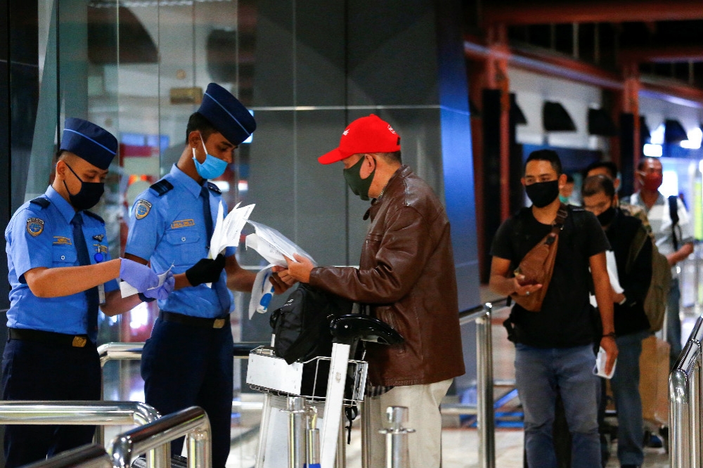 印尼軍警在機場替旅客測量體溫。（湯森路透）