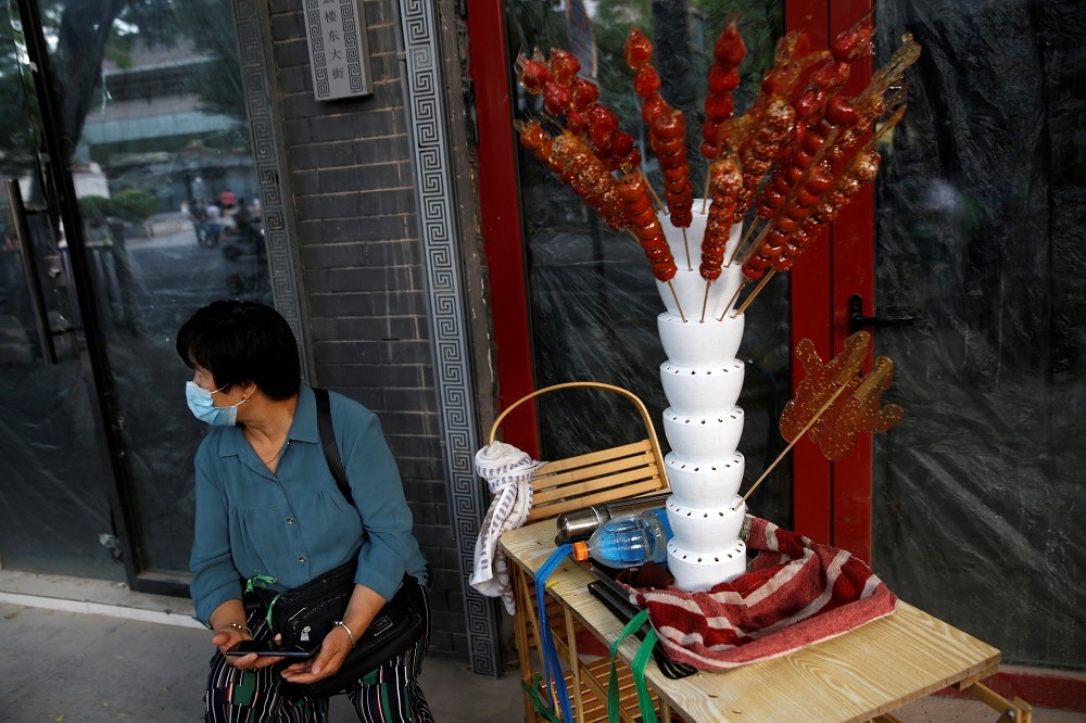 婦人上街販售糖葫蘆等點心。（湯森路透）