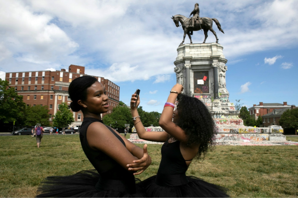 非裔民眾在被大量塗鴉的維州李將軍雕像前跳舞。（湯森路透）