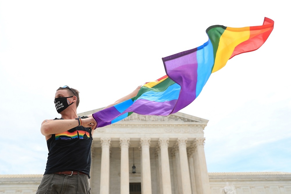 一名男性在美國最高法院前方揮舞彩虹旗。（湯森路透）