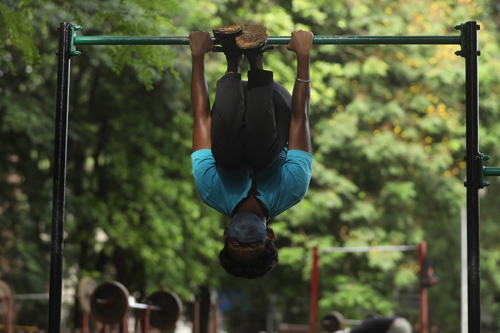 圖為一名印度男子在新冠肺炎疫情期間，在孟買一處公園使用運動器材。（湯森路透）