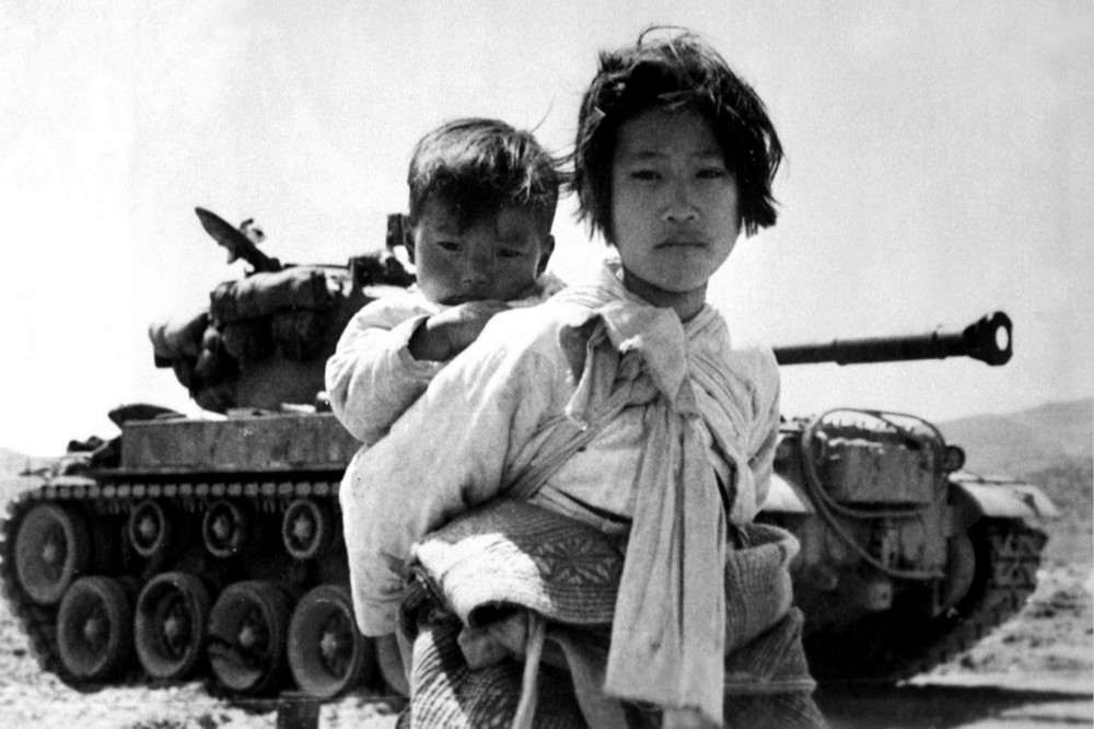 因為戰爭被迫逃難的南韓孩子背著襁褓的弟弟。（圖片取自美國國家檔案局）