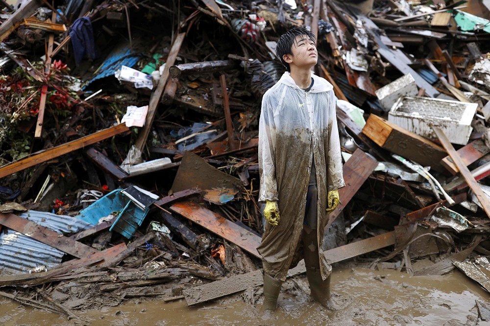 九州熊本縣人吉市一位受災居民協助清理朋友家的殘骸。（湯森路透）