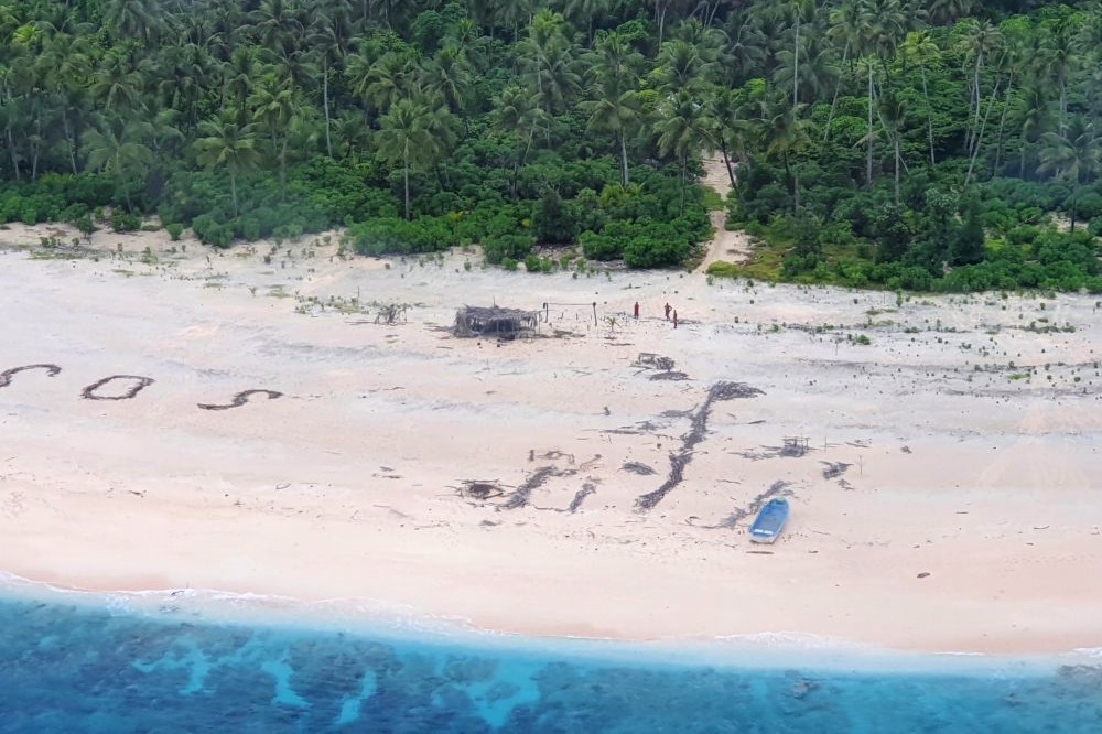太平洋無人小島受困民眾在沙地寫下SOS（左）求救。（湯森路透）