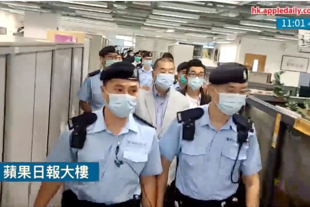 港警押著黎智英進入香港《蘋果日報》大樓進行搜查。（取自影片）