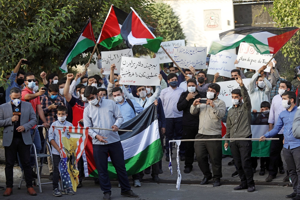 巴勒斯坦人在阿聯大使館前手持燒毀的美國與以色列國旗。（湯森路透）