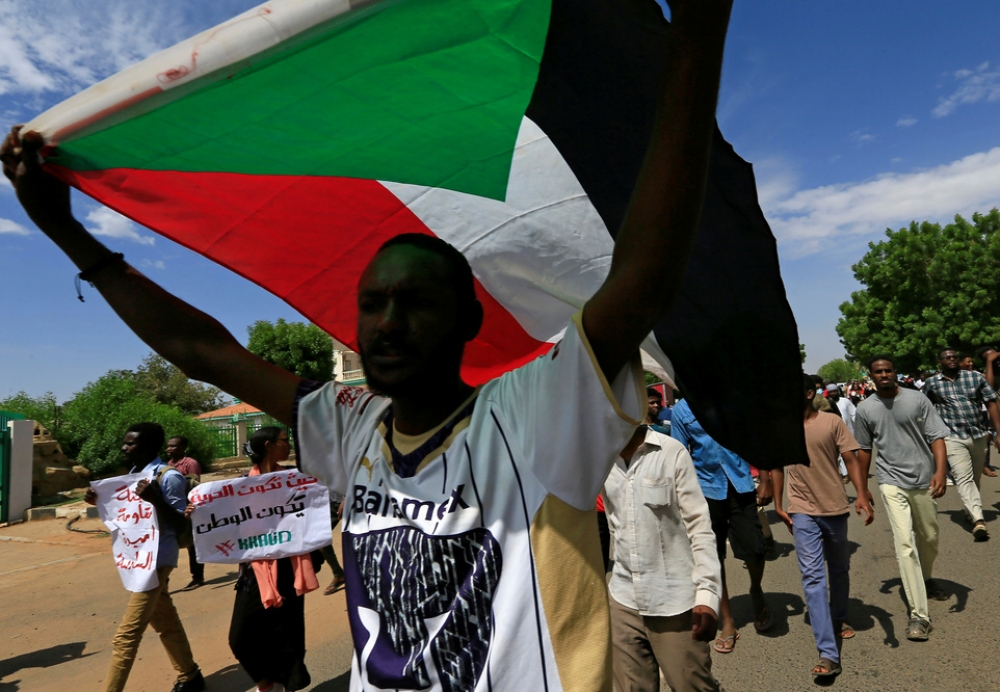 蘇丹示威者17日領著國旗走在喀土木街上，慶祝劃下轉型正義開始的「權利分享協議」簽署一週年。（湯森路透）