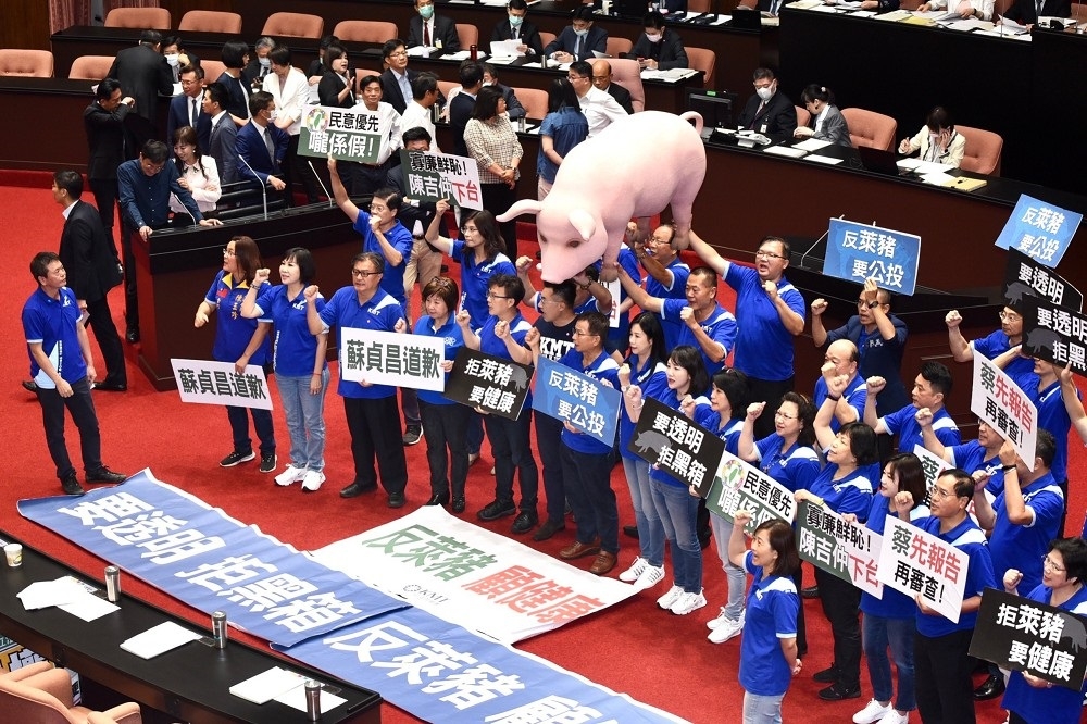 抗議放寬美豬牛進口按，國民黨團抬著粉紅道具豬並高舉標語，在議場發言台前抗議。（張哲偉攝）